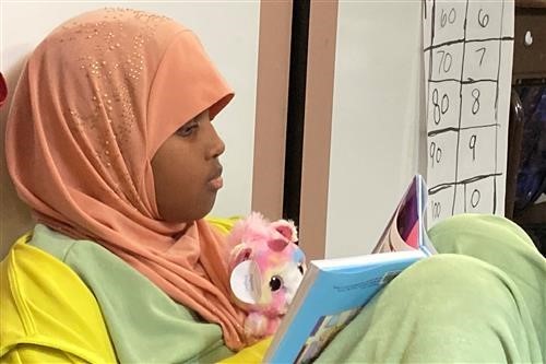 Student reading to a stuffed animal 